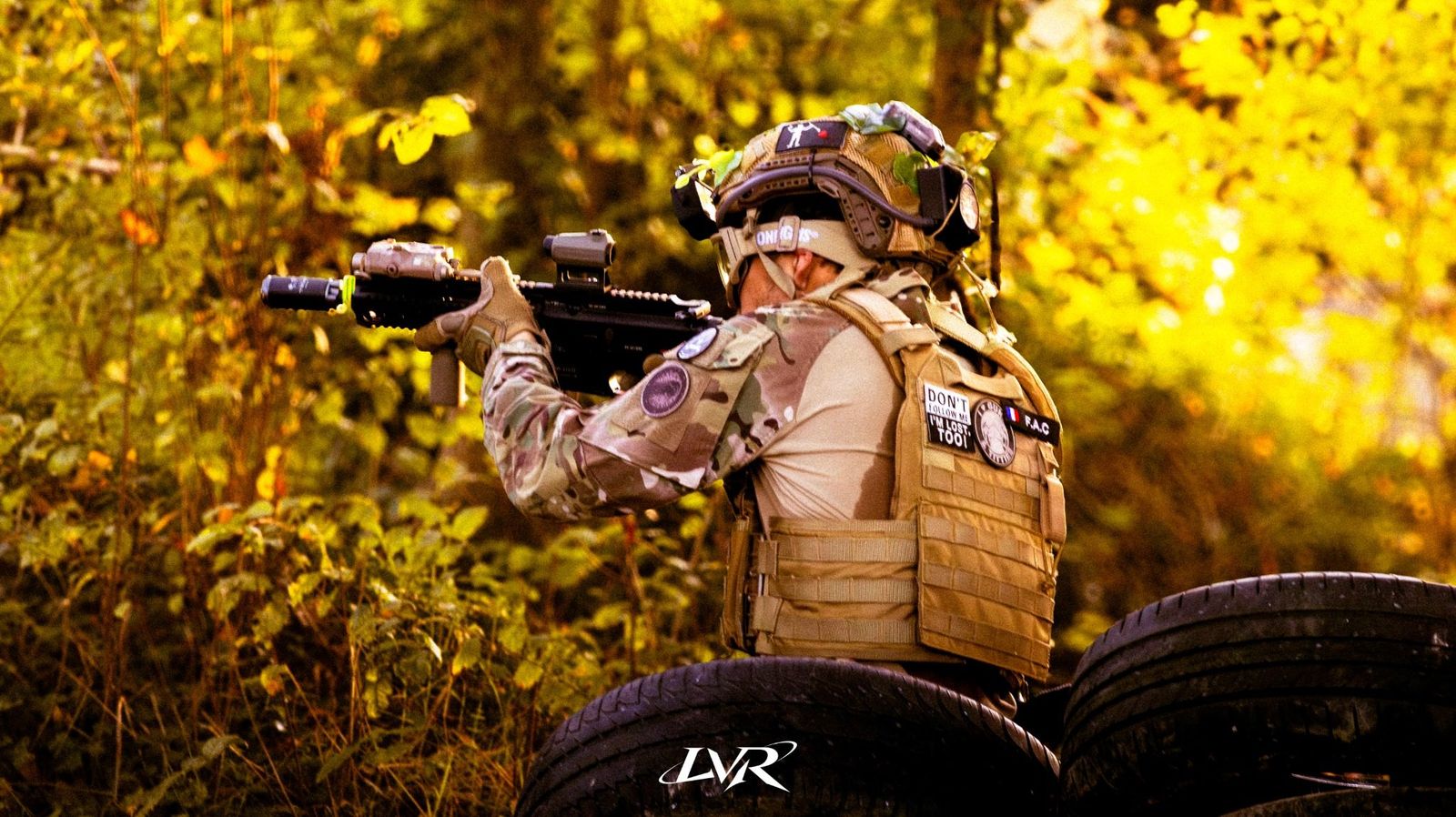 Joueur d’airsoft en tenue camouflage visant en sous-bois
